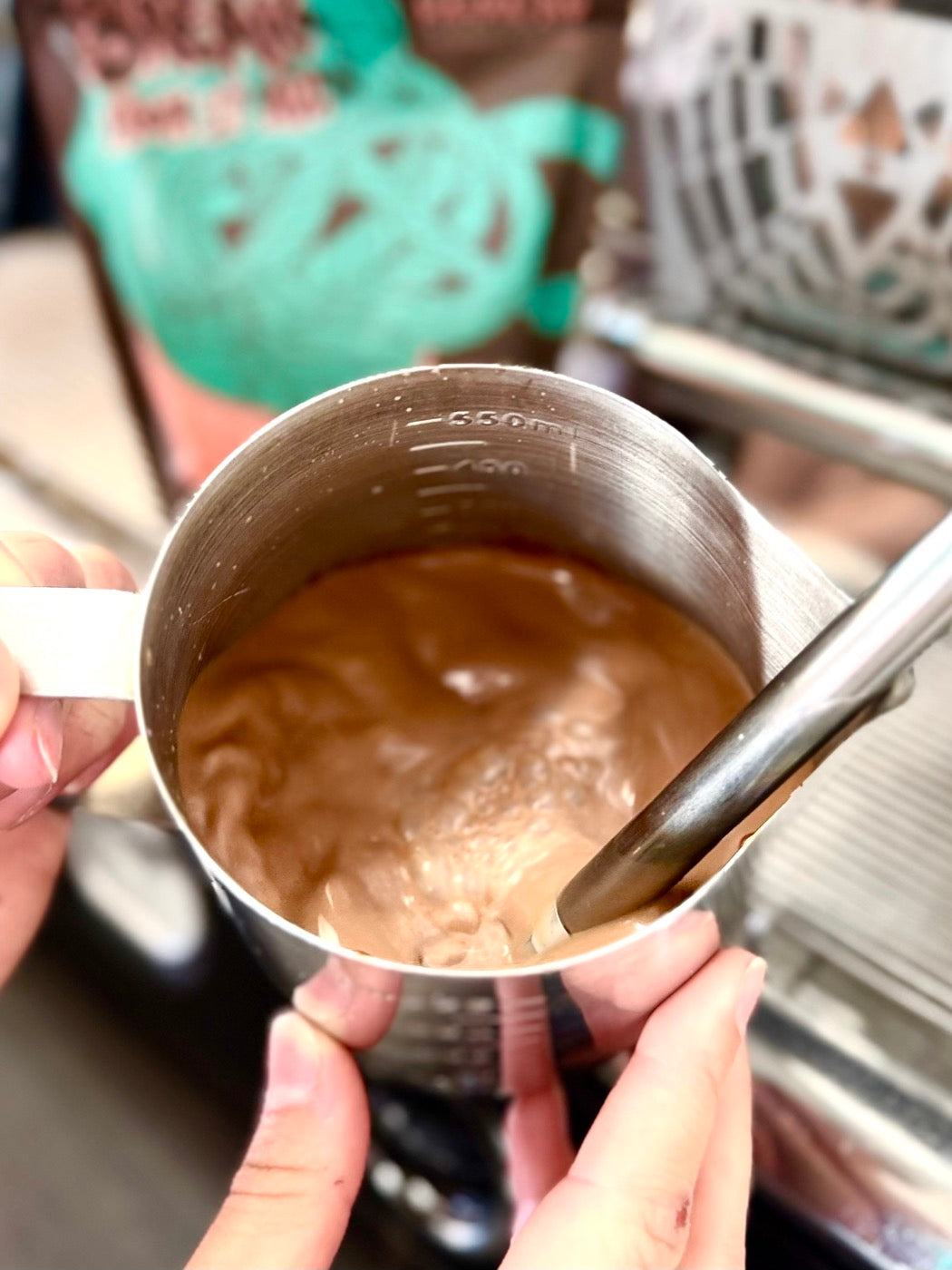 Chocolate drink being steamed in a professional pitcher